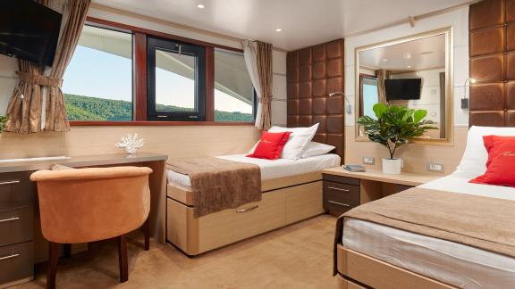 Comfortable twin bed cabin with desk and panoramic window on the motor yacht Queen Eleganza