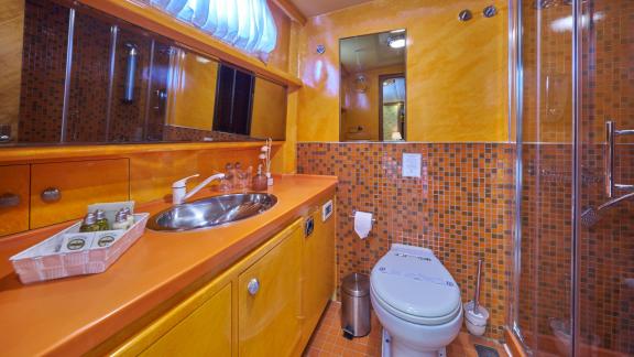 A modern bathroom on board the Gulet Lotus with an elegant mix of orange and mosaic tiles