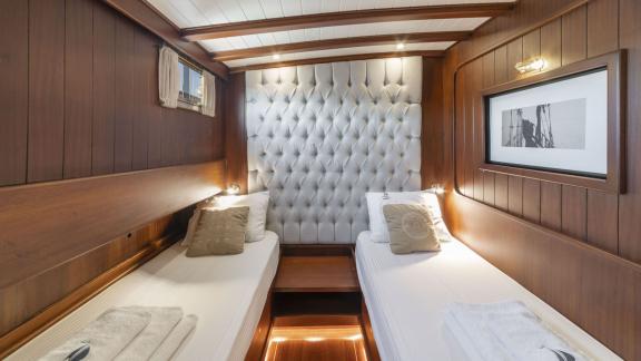 Double cabin of the gulet yacht Jasemin 1 with two single beds and elegant wooden furnishings.