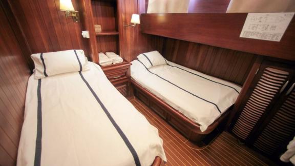 A cabin on board the Gulet Dulcinea with two single beds and stylish wood panelling.