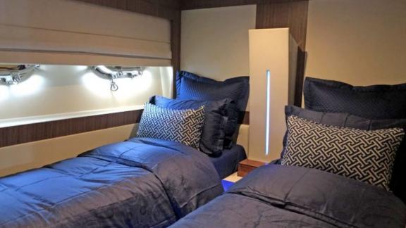 Stylish twin cabin with two single beds and elegant lighting on a motor yacht.