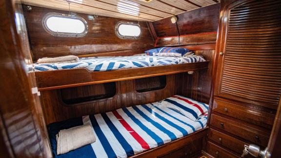 Second cabin on Gulet Thalasa with bunk beds, wood paneling, and porthole windows.