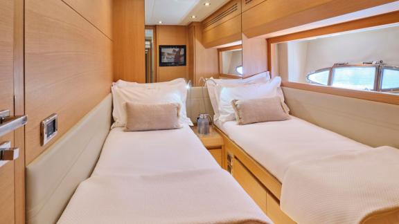 The cabin on Yacht For Ever features twin single beds, wooden details, and side windows.