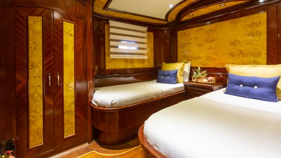 An elegant twin cabin with two single beds, luxurious wood furnishings, and stylish details.