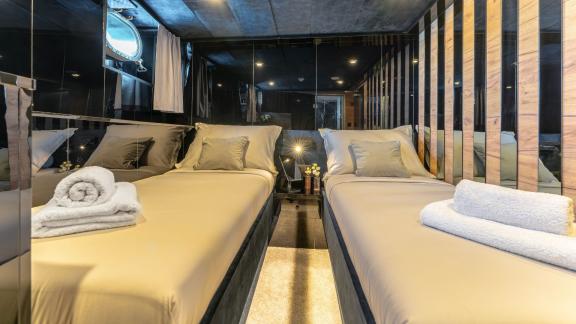 Elegant twin bedroom with mirrored walls and nautical accents.