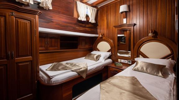 A comfortable cabin with two single beds and elegant wooden furnishings on a gulet in Croatia.