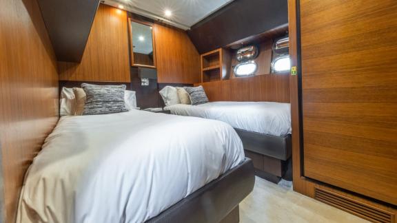 The cabin of the motor yacht Aya One features twin beds and wooden details, creating a comfortable and spacious sleeping