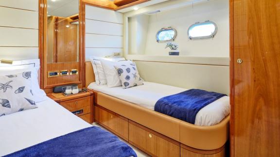 Elegant bedroom on a yacht with twin beds, stylish decor, and porthole windows