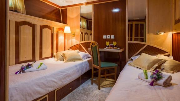 Twin beds and rich wood textures create a warm, inviting space aboard Korab yacht.