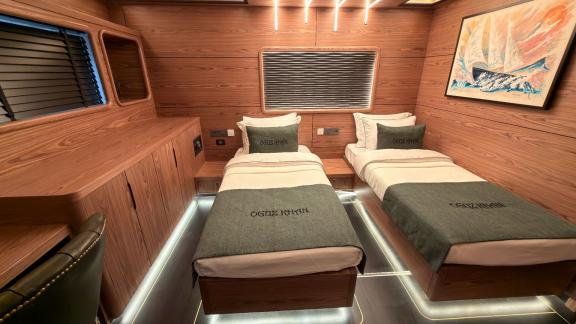 Аренда яхты Oguz Marin в Бодруме каюта с двумя кроватями и картинами для комфортного отдыха 12 гостей на море в Турции.