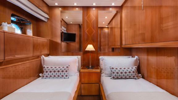 The twin cabin of Dream motor yacht in Athens features two single beds and wooden storage units.