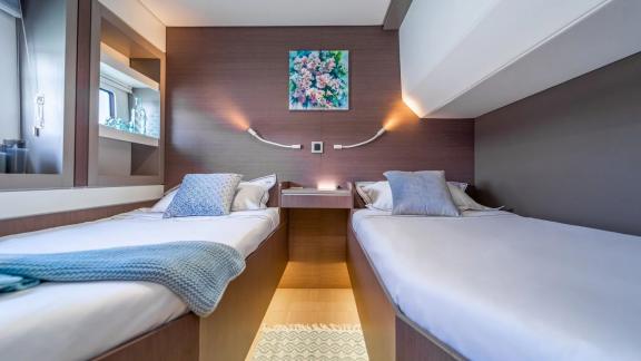 Modern twin cabin with two single beds, stylish decor, and natural light on the Bali Catamaran.