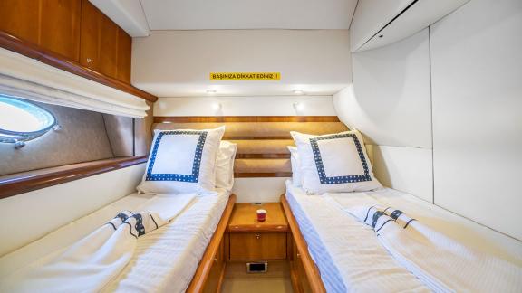 The comfortable cabin on the Edition yacht with twin beds offers stylish bedding and a cozy sleeping area.