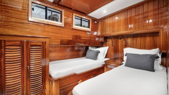 Wood-paneled cabin with two single beds and windows on Serenad A.