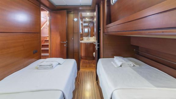 Double cabin with two single beds and wooden panelling on a luxurious sailing yacht.