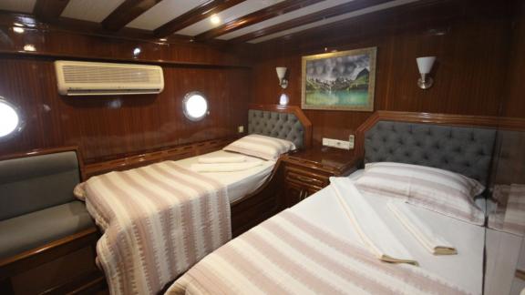 Stylish twin cabin on the Diamond Lila with two single beds, elegant wooden furnishings and a cosy seating area.