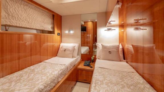 The luxurious guest cabin of the Venus Secrets yacht features twin beds and elegant wooden details.