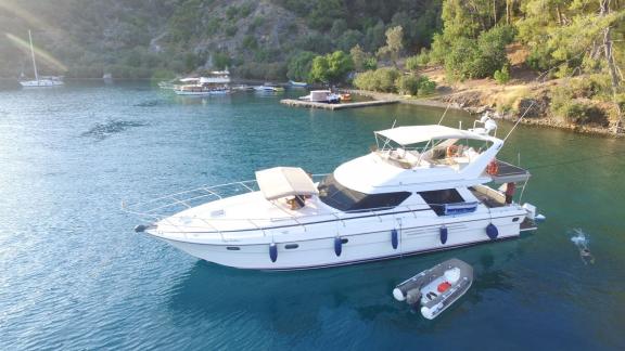 Motoryacht Ayşe Sultan 1 in einer ruhigen Bucht vor Anker, mit einem Boot und anderen Yachten in der Umgebung.