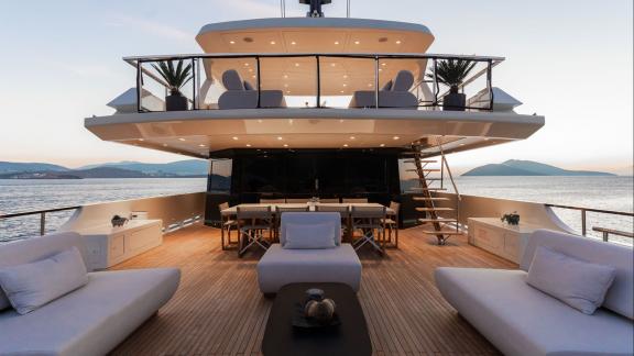 Die Motoryacht Illusion 2 zeigt bei Sonnenuntergang eine elegante Lounge mit Esstisch.
