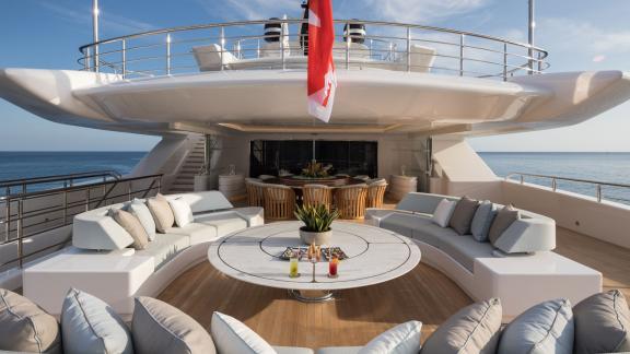 Outdoor lounge on the luxurious yacht Opari with round table, drinks, and ocean views.