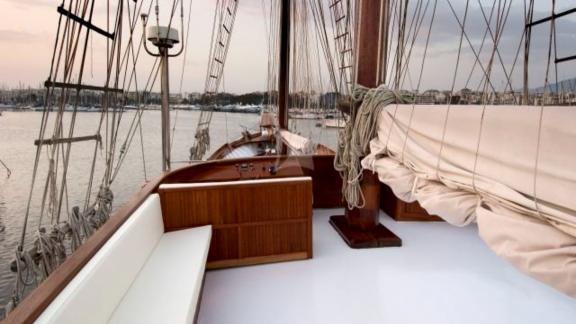 The deck of the gulet Matina in Greece at sunset, with sails at rest and a calm harbour in the background.