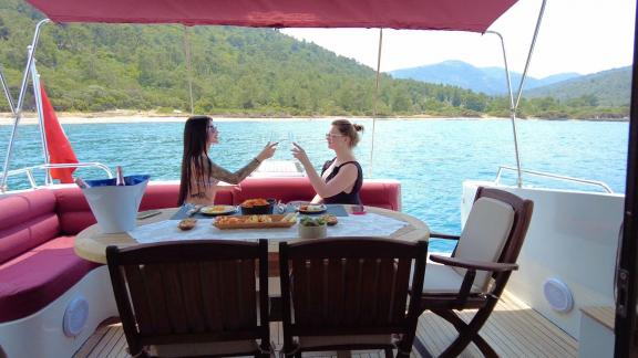 Auf dem Achterdeck der Motoryacht Uranos essen zwei Frauen mit Blick auf das Meer.