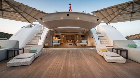 Sun loungers, seating furniture, sun umbrellas, and water scooters on the sun deck of a yacht with views of the sea and 