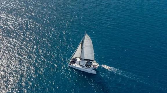 Aerialaufnahme der Segelyacht Vamos, die in den ruhigen, blauen Gewässern von Fethiye segelt, begleitet von einem Beiboo