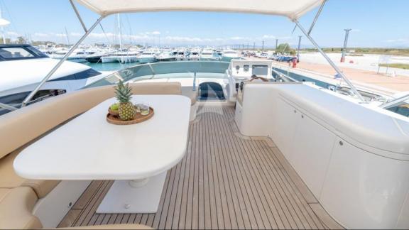 On the deck of the Venus Secrets yacht, comfortable seating and a table provide a spacious environment.