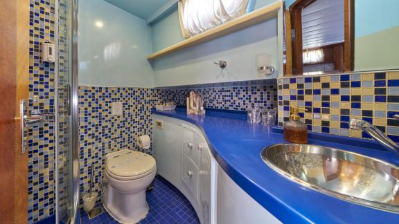 The modern bathroom of the Gulet Lotus, designed in blue tones with stylish mosaic tiles, a spacious washbasin and a sho