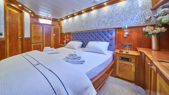 The luxurious guest cabin of the Gulet Lotus in Croatia, with a large bed, stylish wooden furniture and a private bathro