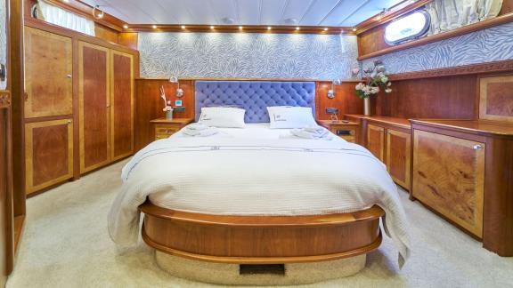 The elegant guest cabin of the Gulet Lotus is equipped with a comfortable bed and high-quality wooden furniture.