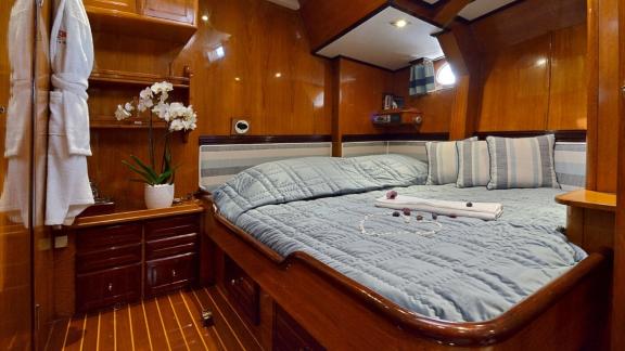 Die Gästekabine der Luxusyacht Wind Of Change verfügt über Bademäntel, Holzakzente und ein komfortables Bett.