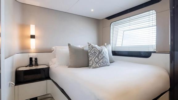 Spacious modern cabin on Nemesis yacht featuring large window and cozy bed for a peaceful rest.