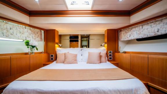 На яхте Ferretti 780 Orlando L уютная каюта с деревянной отделкой и большим окном.