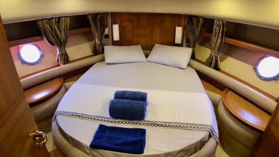 Gemütliches Schlafzimmer auf der Motoryacht Cosmos mit stilvollem Design und Fenstern mit Meerblick.