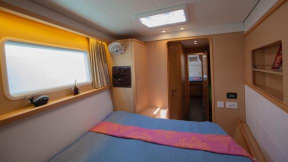 A bright and spacious cabin on a Lagoon 560 catamaran in Göcek, featuring a double bed, a skylight, and a small shelf, o