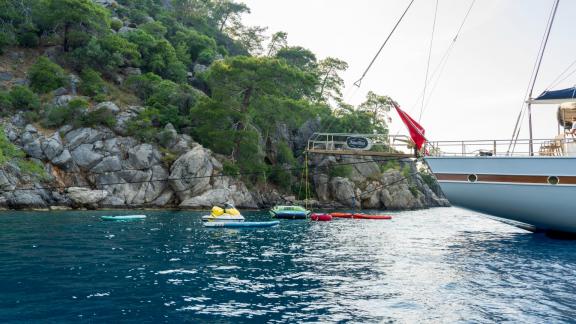 Fethiye'deki 5 kabinli lüks yelkenli tekne, kayalık bir kıyı açıklarında çeşitli su sporları aktiviteleri sağlamaktadır.