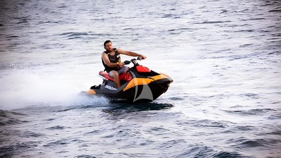 A person enjoys water sports by riding a jet ski on the Hasard yacht.