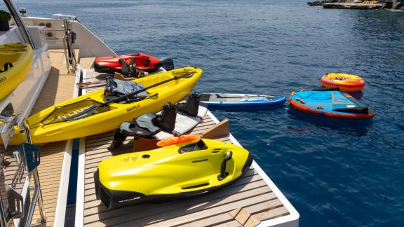 Kayaks, jet skis, and water toys on a catamaran ready for use on the sea.