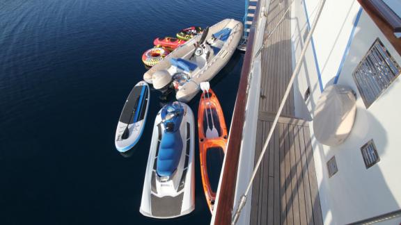 Ece Berrak guletinin yanında jet ski ve kano gibi çeşitli su sporları ekipmanları demirli.