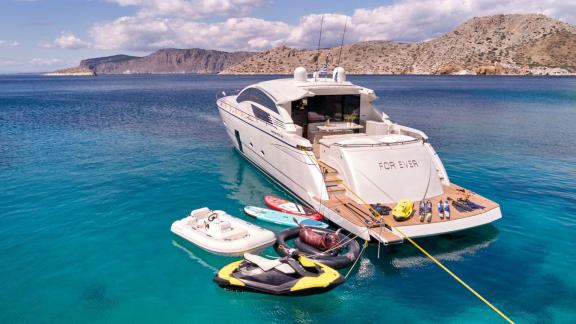 The For Ever yacht is anchored over pristine blue waters, surrounded by various water toys.