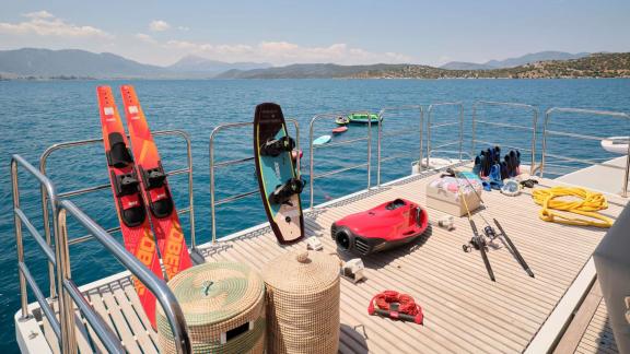 Various watersports gear, including waterskis and a wakeboard, on the deck of the Genny catamaran.