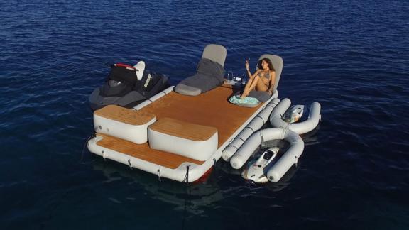 Eine Gästin entspannt auf der Plattform mit Jetski und Wasserzubehör. Angedockt an die Charteryacht im Meer.