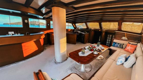 A luxurious interior of a sailing ship with cosy sofas, an elegant bar and large windows with sea views.