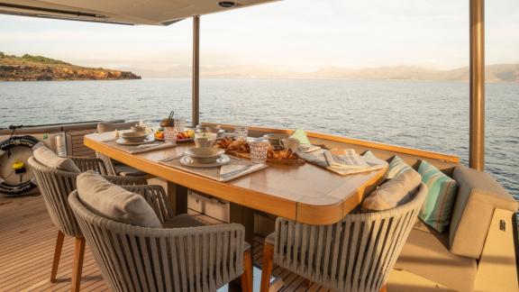 A carefully set breakfast table on the Ammonite motor yacht with a view of the sea.