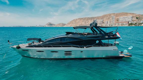 The Ammonite motor yacht anchored in calm waters with a coastal view.