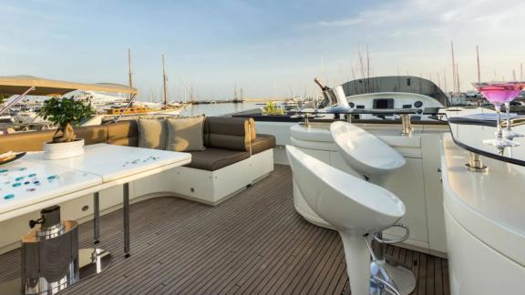 The upper deck of yacht Amoraki features a bar and seating area.