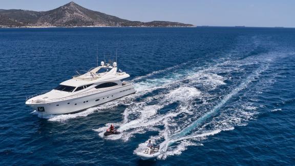 Luxurious motor yacht on the open sea, accompanied by a jet ski and a dinghy.