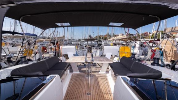 The aft deck of the yacht Anse features a spacious seating area and dining table, anchored in the marina.